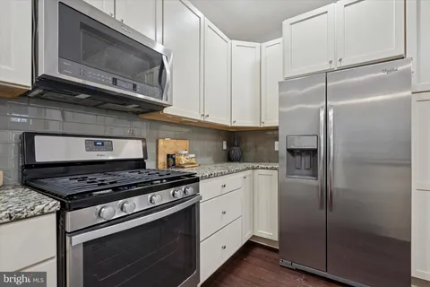 a kitchen with stainless steel appliances granite countertop a stove a microwave and a refrigerator