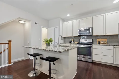 a kitchen with granite countertop white cabinets and chairs