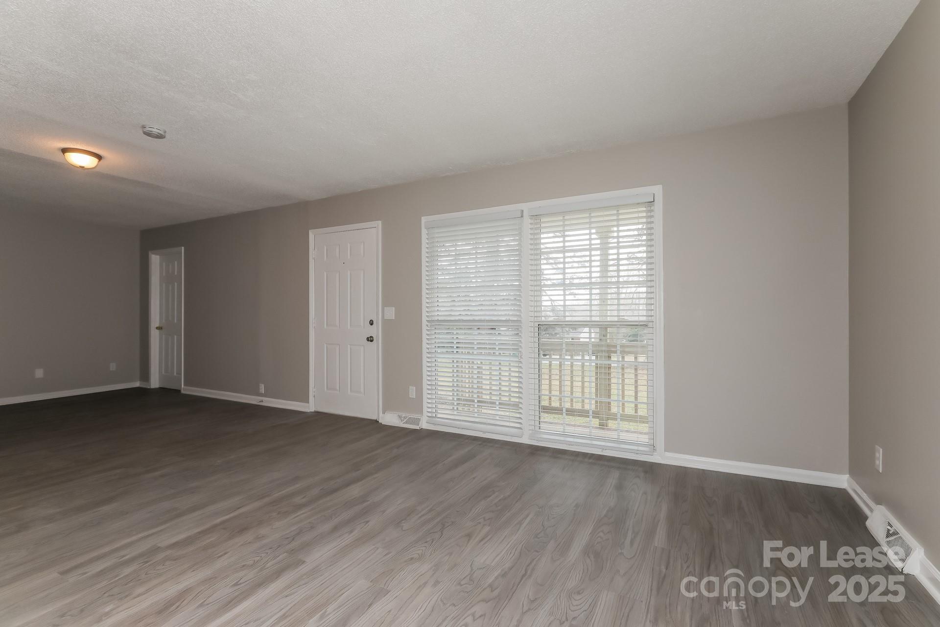 319 Cedarwood Lane Matthews, NC 28104 - Photo 4 of 16 an empty room with wooden floor and windows