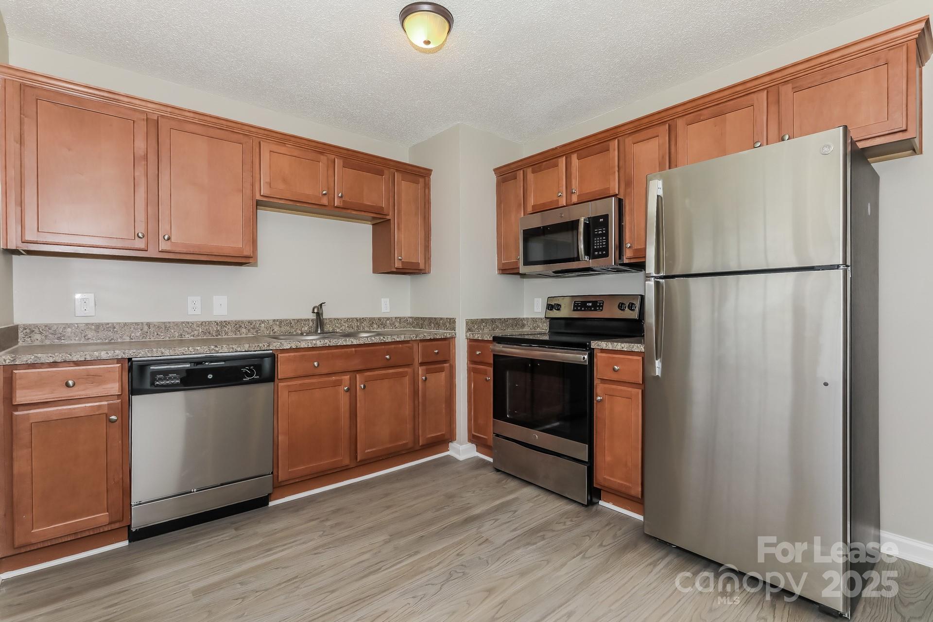 319 Cedarwood Lane Matthews, NC 28104 - Photo 5 of 16 a kitchen with granite countertop a refrigerator stove and microwave