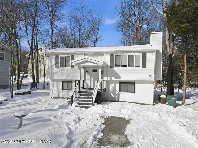 a front view of a house with a yard covered in snow