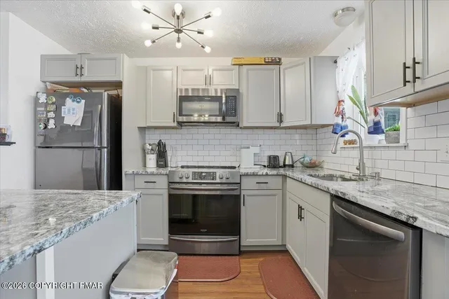 a kitchen with granite countertop a sink stainless steel appliances wooden floor and cabinets