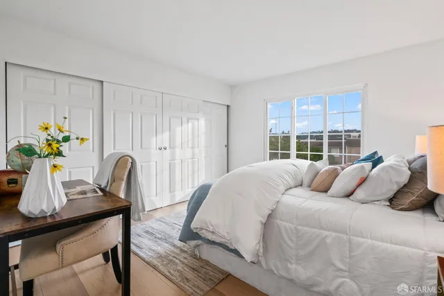 a bedroom with a bed table chair and a window