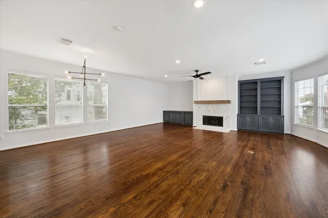 an empty room with wooden floor fireplace and windows