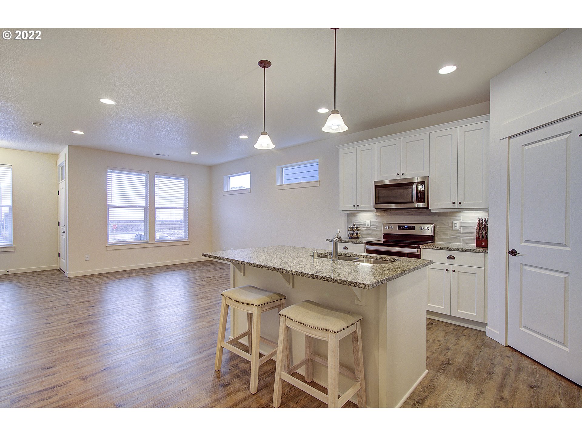 7107 South 11th Street Ridgefield, WA 98642 - Photo 7 of 26 a kitchen with stainless steel appliances a stove a sink a refrigerator with white cabinets and wooden floor