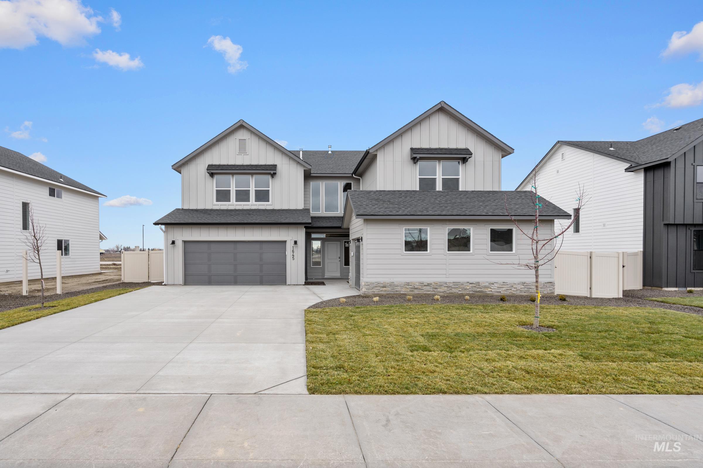 Modern inspired farmhouse featuring board and batten siding, an attached garage, driveway, and roof with shingles
