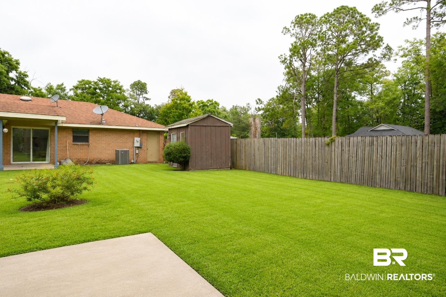 614 East Gate Circle Foley, AL 36535 - Photo 31 of 31 Expansive backyard featuring a large concrete patio, lush green lawn, full privacy fencing, a storage shed, and mature perimeter trees