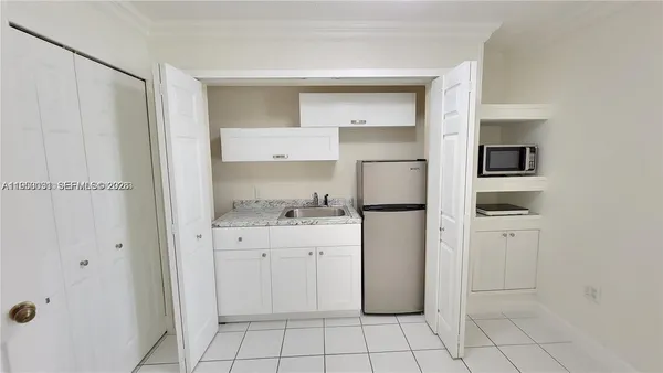 a kitchen with white cabinets and refrigerator