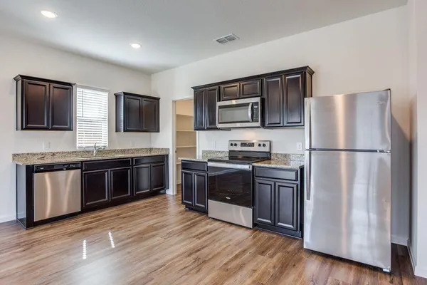 a kitchen with stainless steel appliances granite countertop a refrigerator stove a sink dishwasher and microwave