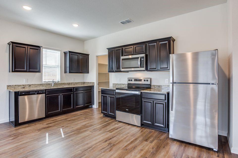 1815 Wolf Run Anna, TX 75409 - Photo 2 of 11 a kitchen with stainless steel appliances granite countertop a refrigerator stove a sink dishwasher and microwave