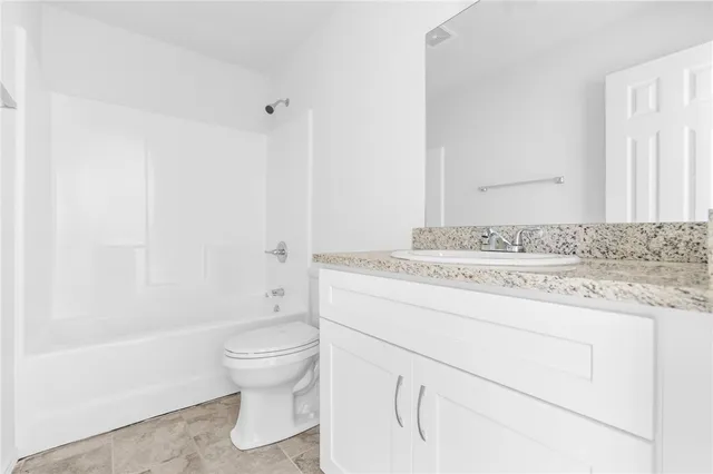 a bathroom with a granite countertop sink a toilet and a bathtub