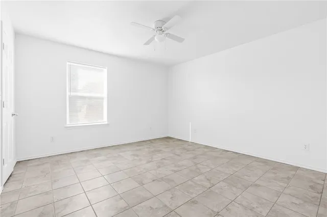 an empty room with windows and fan