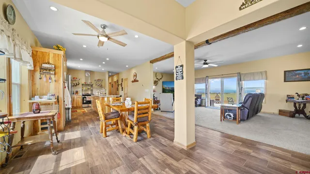 a living room with lots of dining furniture kitchen view and a large window