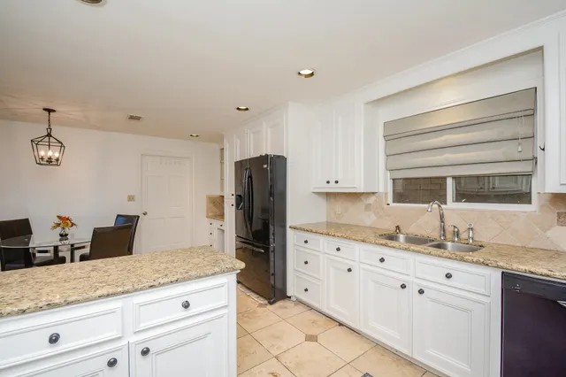 a kitchen with granite countertop a sink stainless steel appliances white cabinets and a window