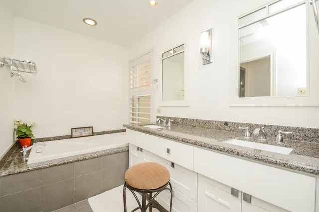 a bathroom with a granite countertop sink and a bathtub