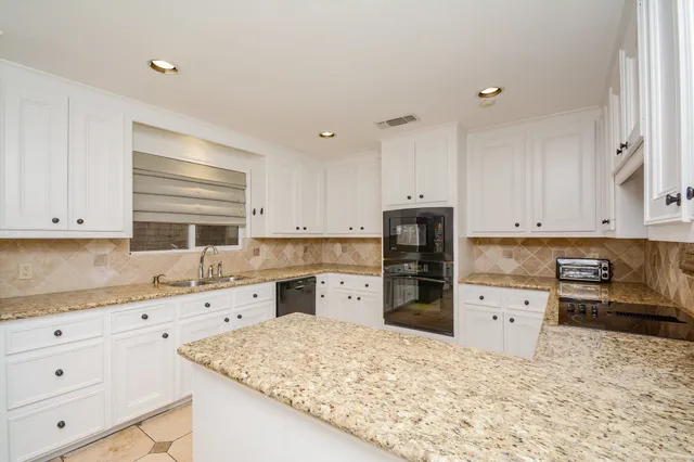 a kitchen with granite countertop a refrigerator sink stove and cabinets