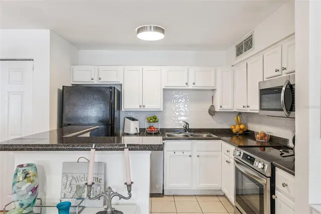 a kitchen with stainless steel appliances granite countertop a sink stove refrigerator and cabinets
