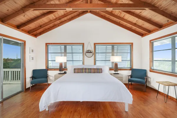 a large bedroom with wooden floor and large windows