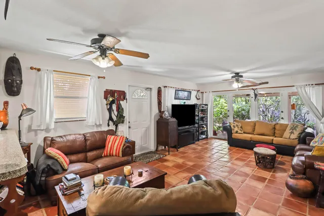 a living room with furniture a ceiling fan a fireplace and a large window
