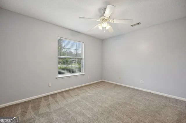 an empty room with a chandelier fan and windows