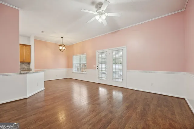 a view of an empty room with window and wooden floor