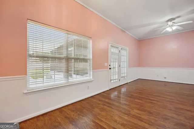 a view of an empty room with wooden floor and a window