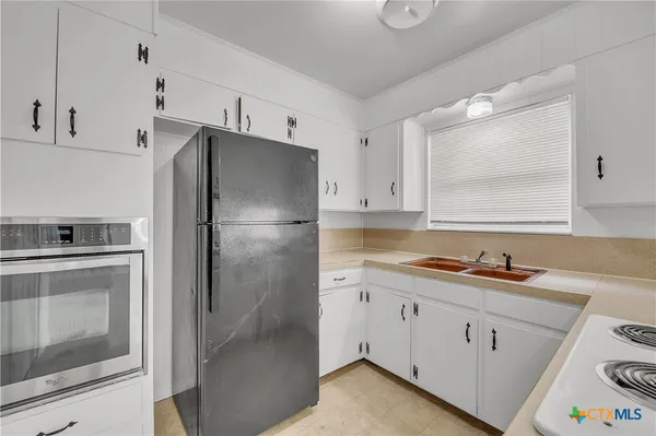 a kitchen with a refrigerator sink and cabinets
