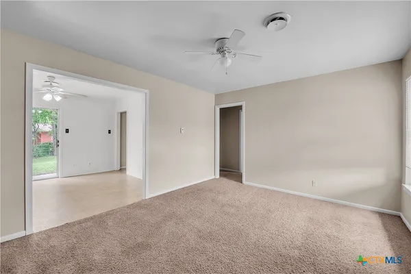 a view of an empty room and a chandelier fan