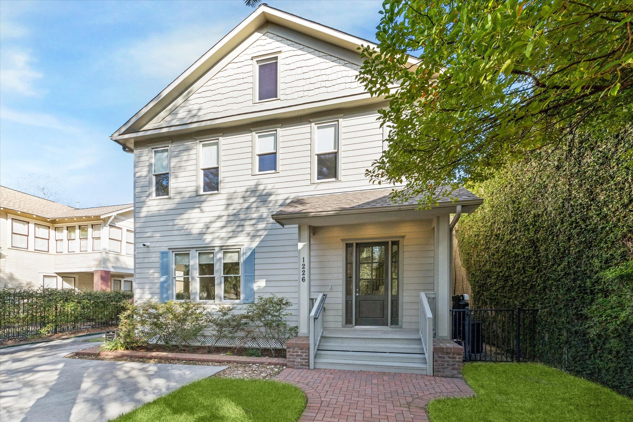Classic Heights-style façade with charming architectural details and a welcoming covered front porch. Mature landscaping and a brick walkway enhance the home’s curb appeal.