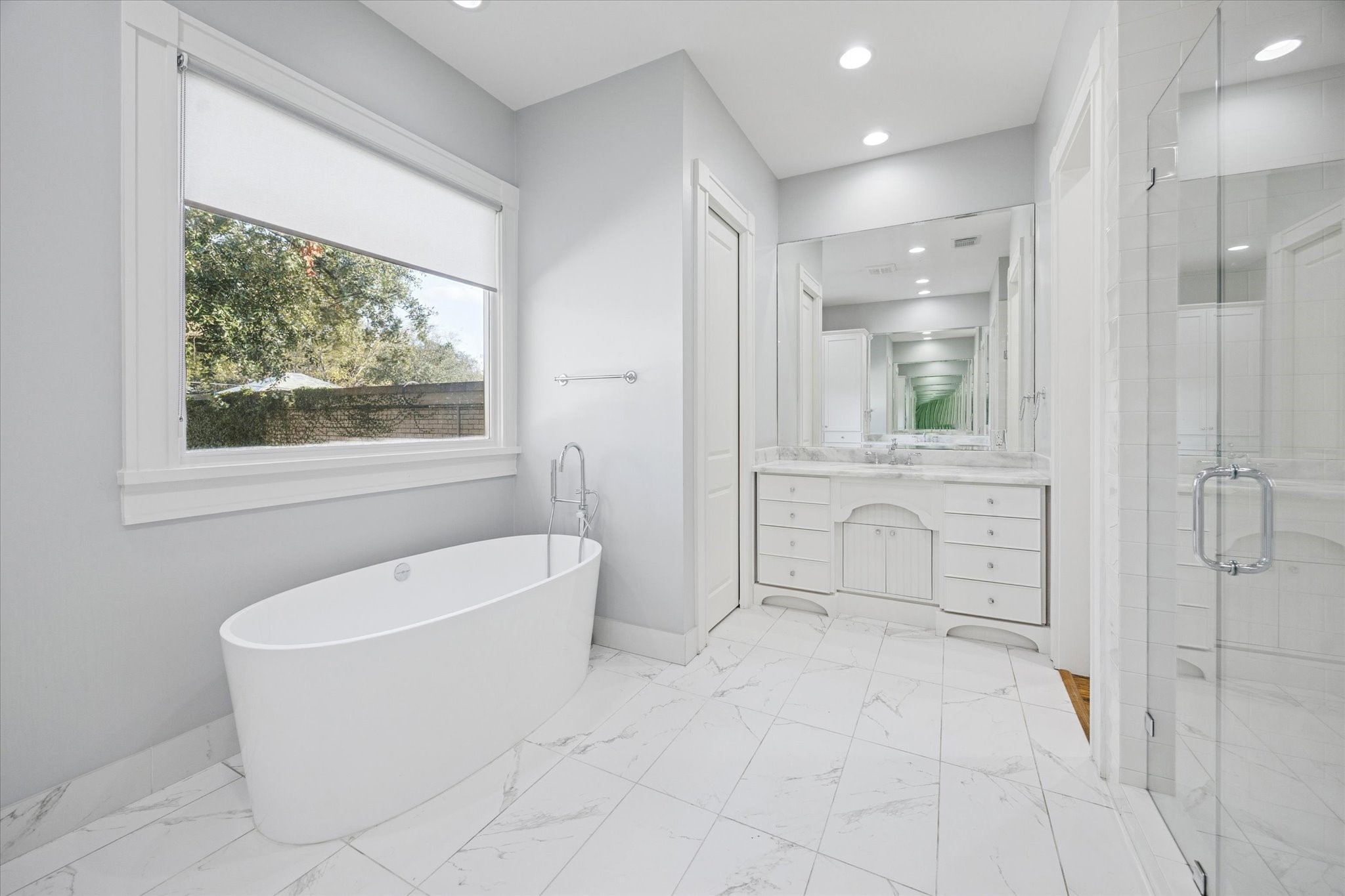 1226 Heights Boulevard Houston, TX 77008 - Photo 24 of 40 Spa-like primary bathroom includes a freestanding soaking tub, marble-look tile flooring, and abundant natural light. Designed for relaxation and everyday comfort.