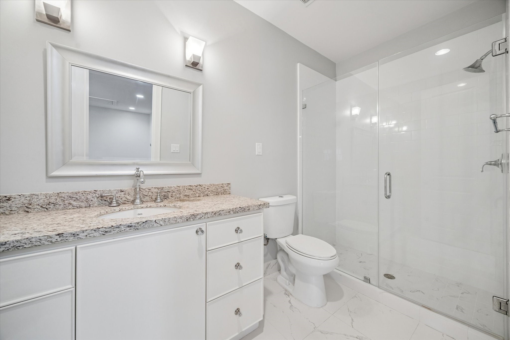 1226 Heights Boulevard Houston, TX 77008 - Photo 29 of 40 Garage apartment bathroom offers granite countertop vanity, framed mirror, and walk-in shower with tile surround. Finished with neutral tones and modern fixtures.