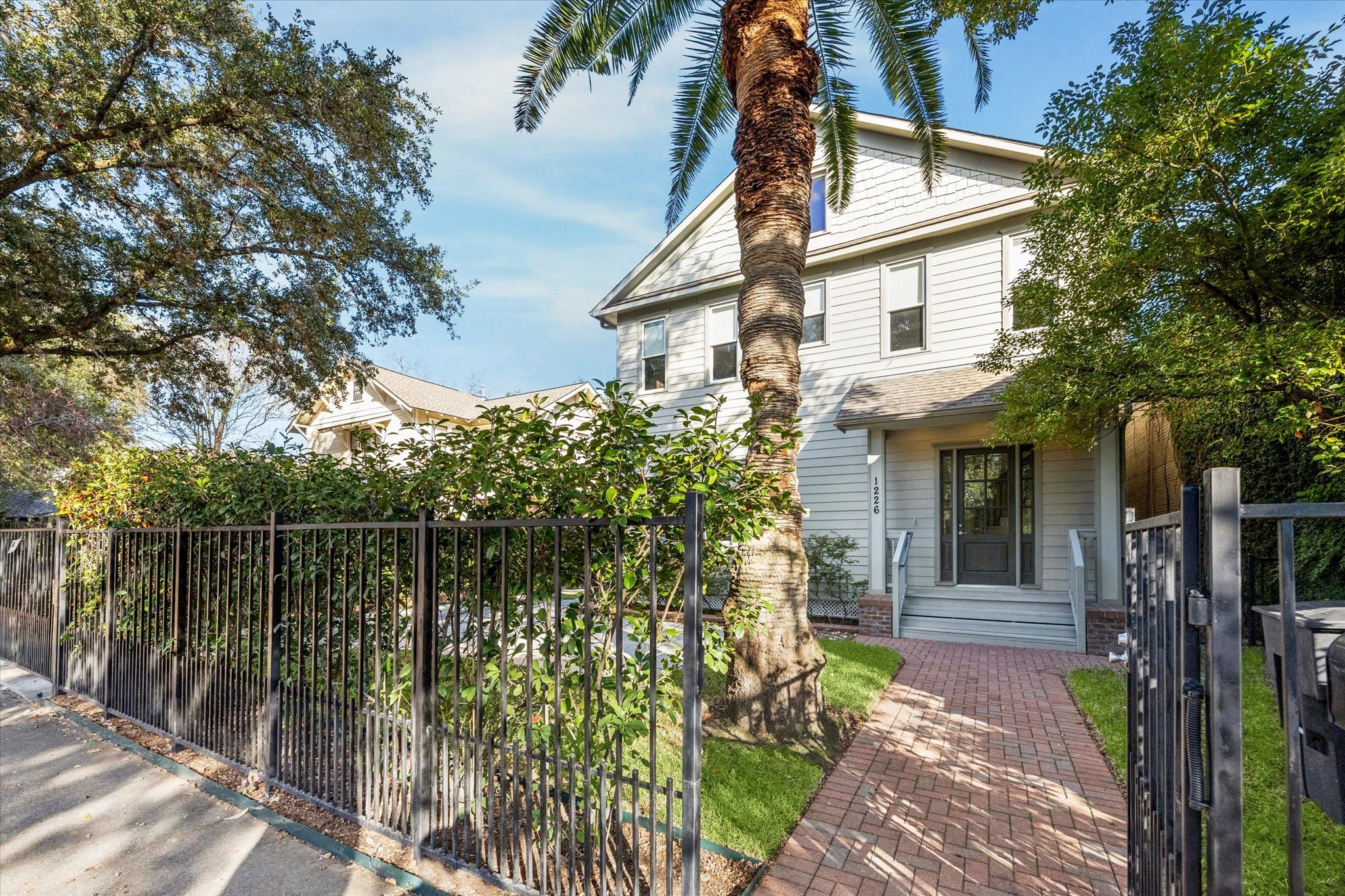 1226 Heights Boulevard Houston, TX 77008 - Photo 3 of 40 Secure gated entrance leads to a picturesque brick walkway and manicured front lawn. Mature trees and fencing create a peaceful, private setting.