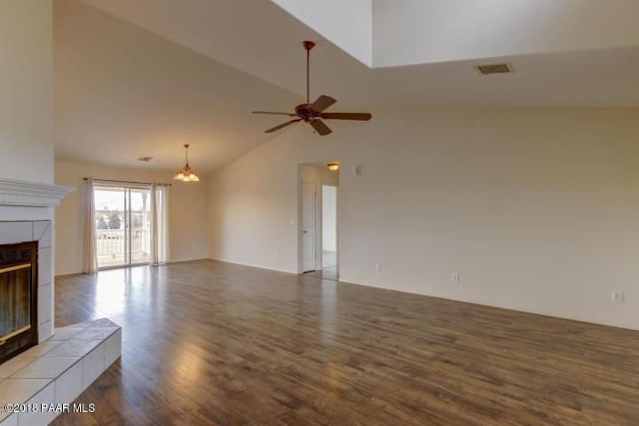 2165 West Lazy Ranch Road Chino Valley, AZ 86323 - Photo 3 of 17 an empty room with wooden floor a ceiling fan and a fireplace