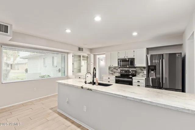 a large kitchen with kitchen island granite countertop a large counter top stainless steel appliances and cabinets