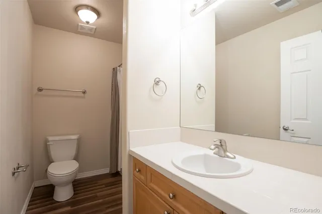 a bathroom with a granite countertop sink toilet and mirror