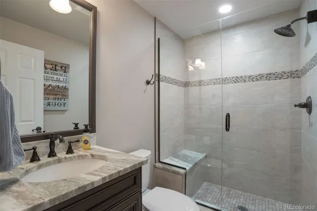 a bathroom with a granite countertop sink toilet and shower