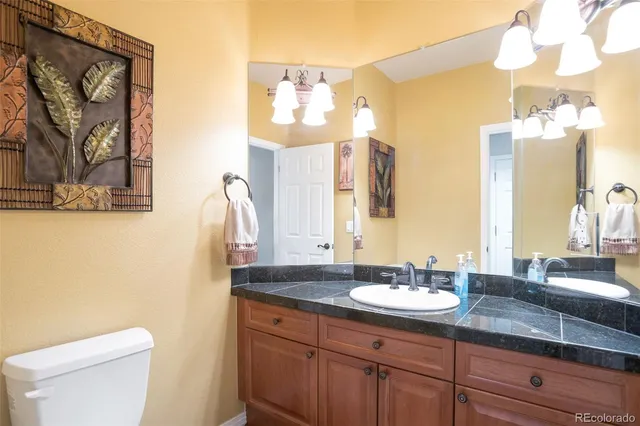 a bathroom with a granite countertop sink toilet and a mirror