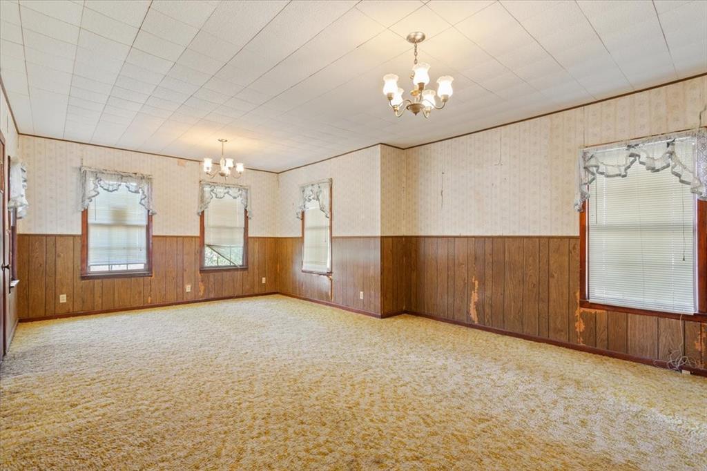 100 County Road 120 C Riesel, TX 76682 - Photo 7 of 25 Carpeted empty room featuring a chandelier, a wainscoted wall, wallpapered walls, and wood walls
