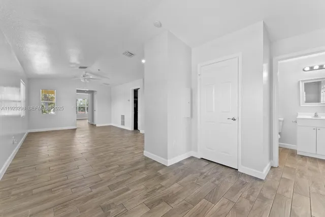 a view of an empty room with window and wooden floor