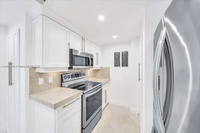 a kitchen with stainless steel appliances white cabinets and a refrigerator