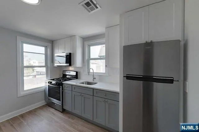 a kitchen with a refrigerator a sink and wooden floor