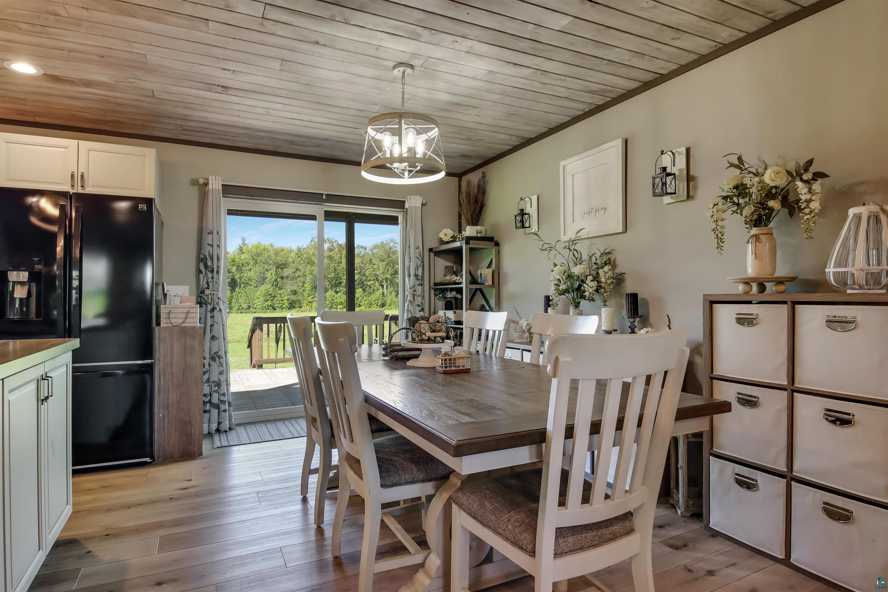 N3685 Fenander Road Spooner, WI 54801 - Photo 16 of 38 Dining space with light wood-type flooring, wood ceiling, crown molding, and a chandelier