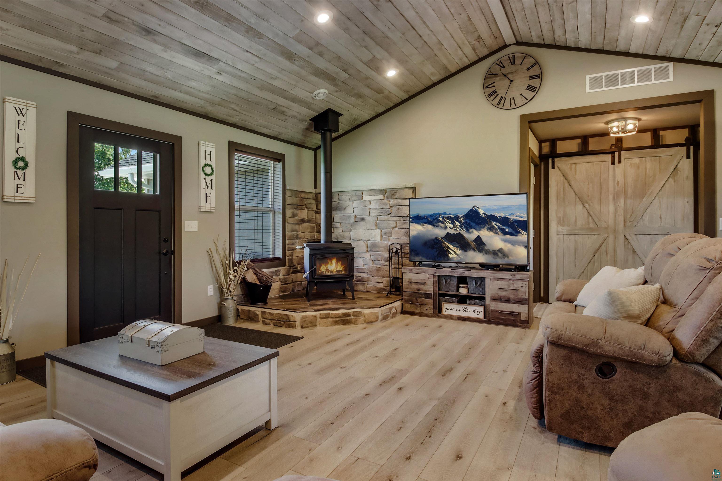 N3685 Fenander Road Spooner, WI 54801 - Photo 17 of 38 Living room with light hardwood / wood-style flooring, a wood stove, wood ceiling, lofted ceiling, and a barn door