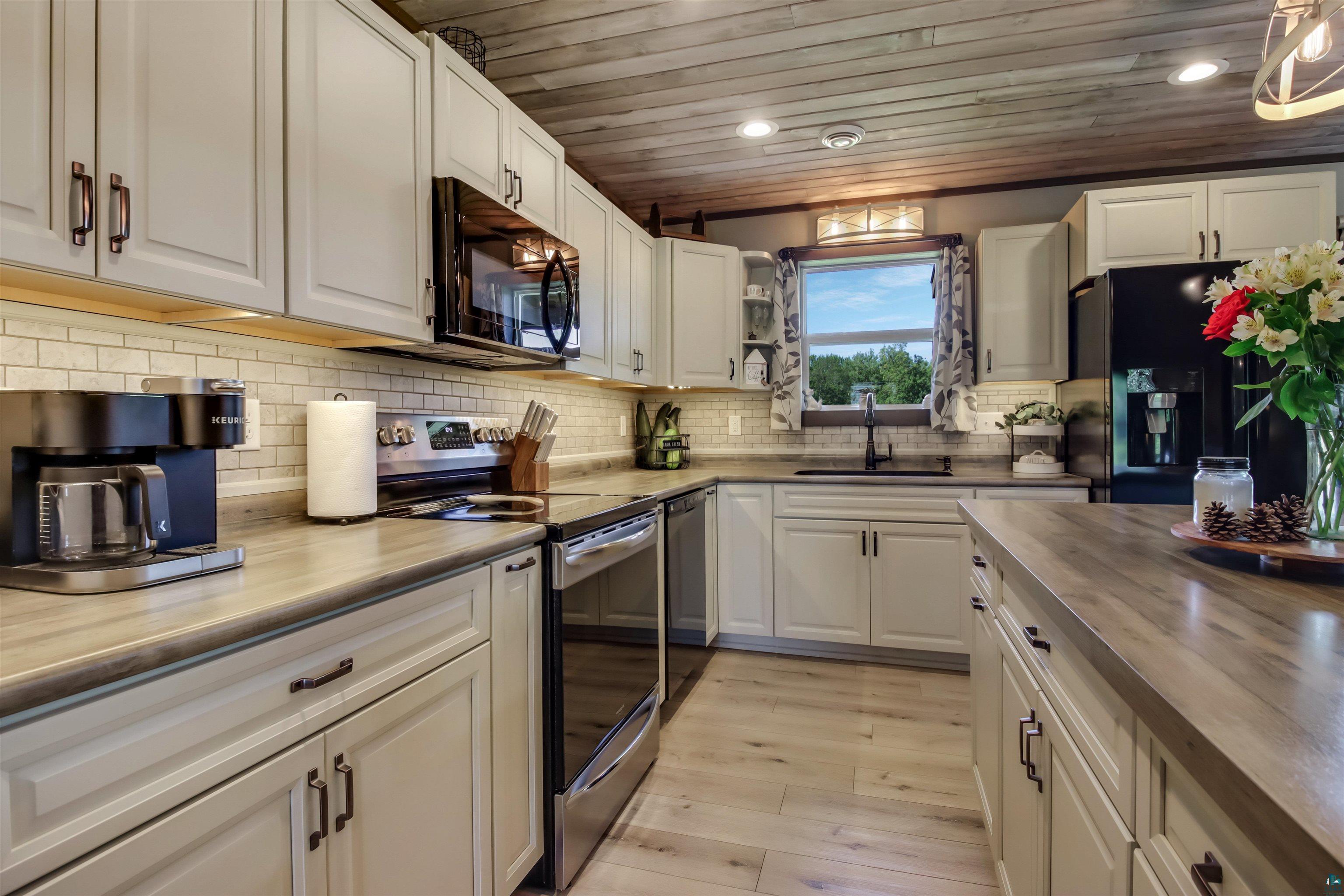 N3685 Fenander Road Spooner, WI 54801 - Photo 20 of 38 Kitchen featuring wooden ceiling, black appliances, sink, and white cabinets