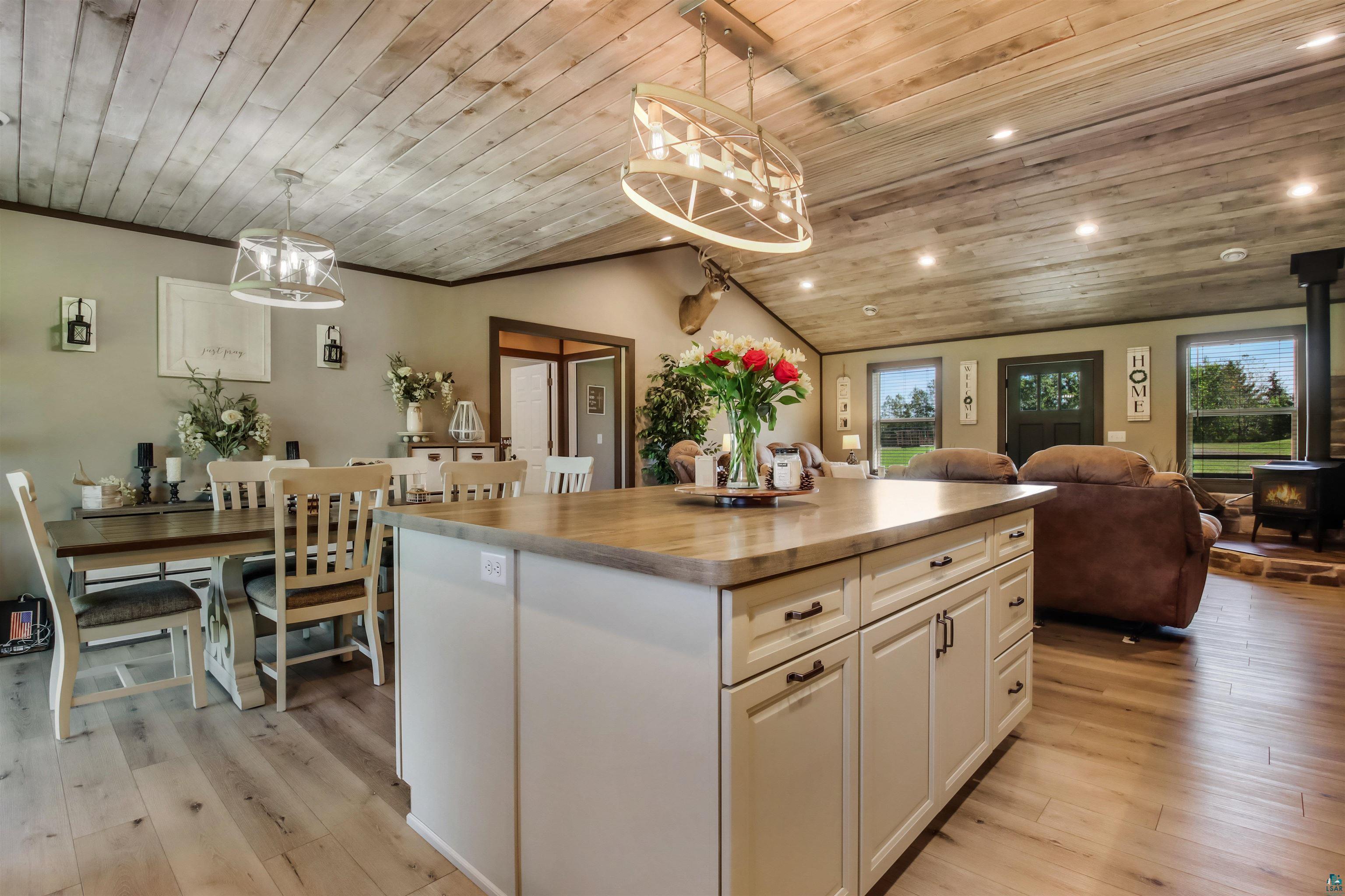 N3685 Fenander Road Spooner, WI 54801 - Photo 22 of 38 Kitchen with pendant lighting, a wood stove, wood ceiling, lofted ceiling, and a center island with sink