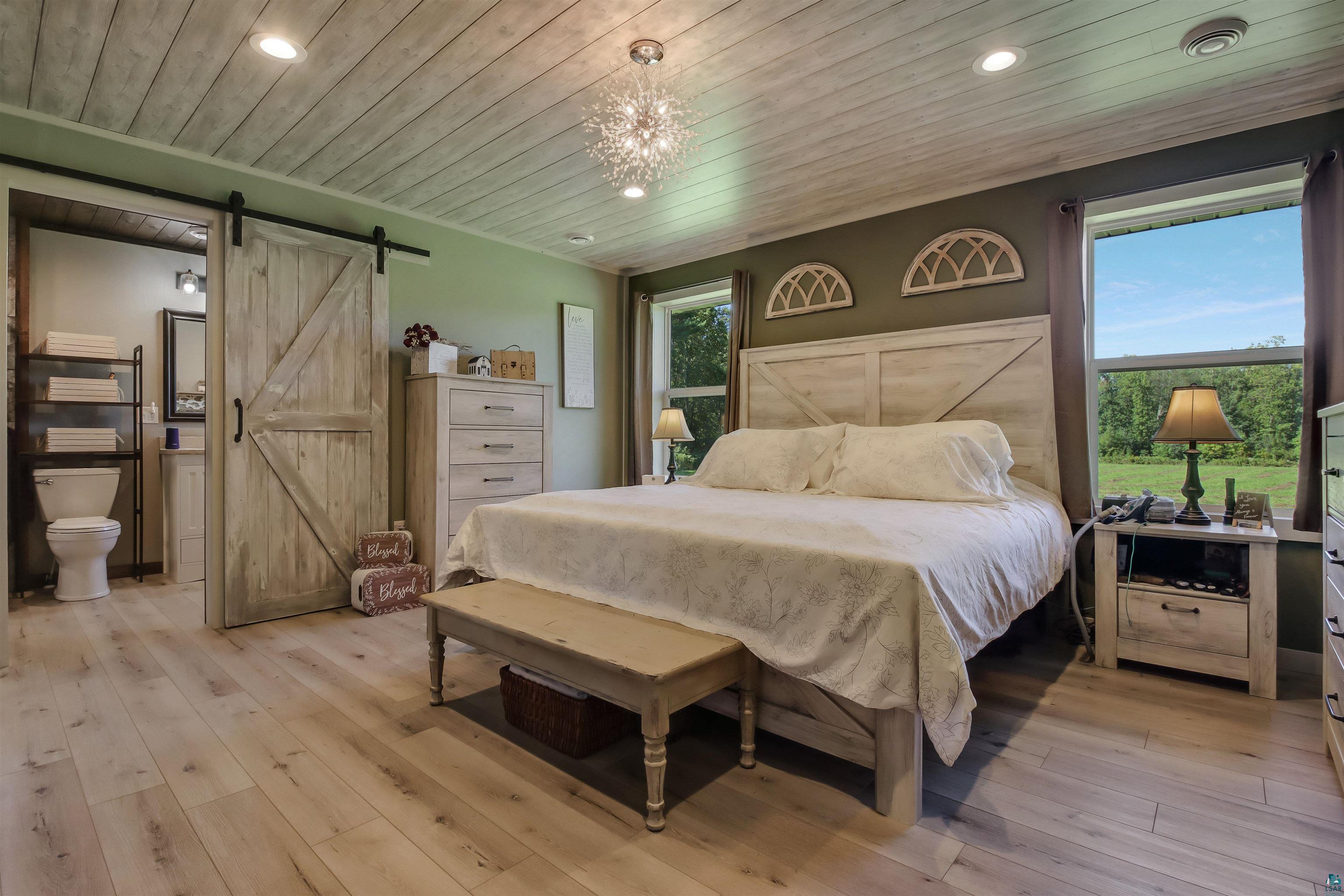 N3685 Fenander Road Spooner, WI 54801 - Photo 25 of 38 Bedroom featuring a barn door, wooden ceiling, light wood-type flooring, and multiple windows