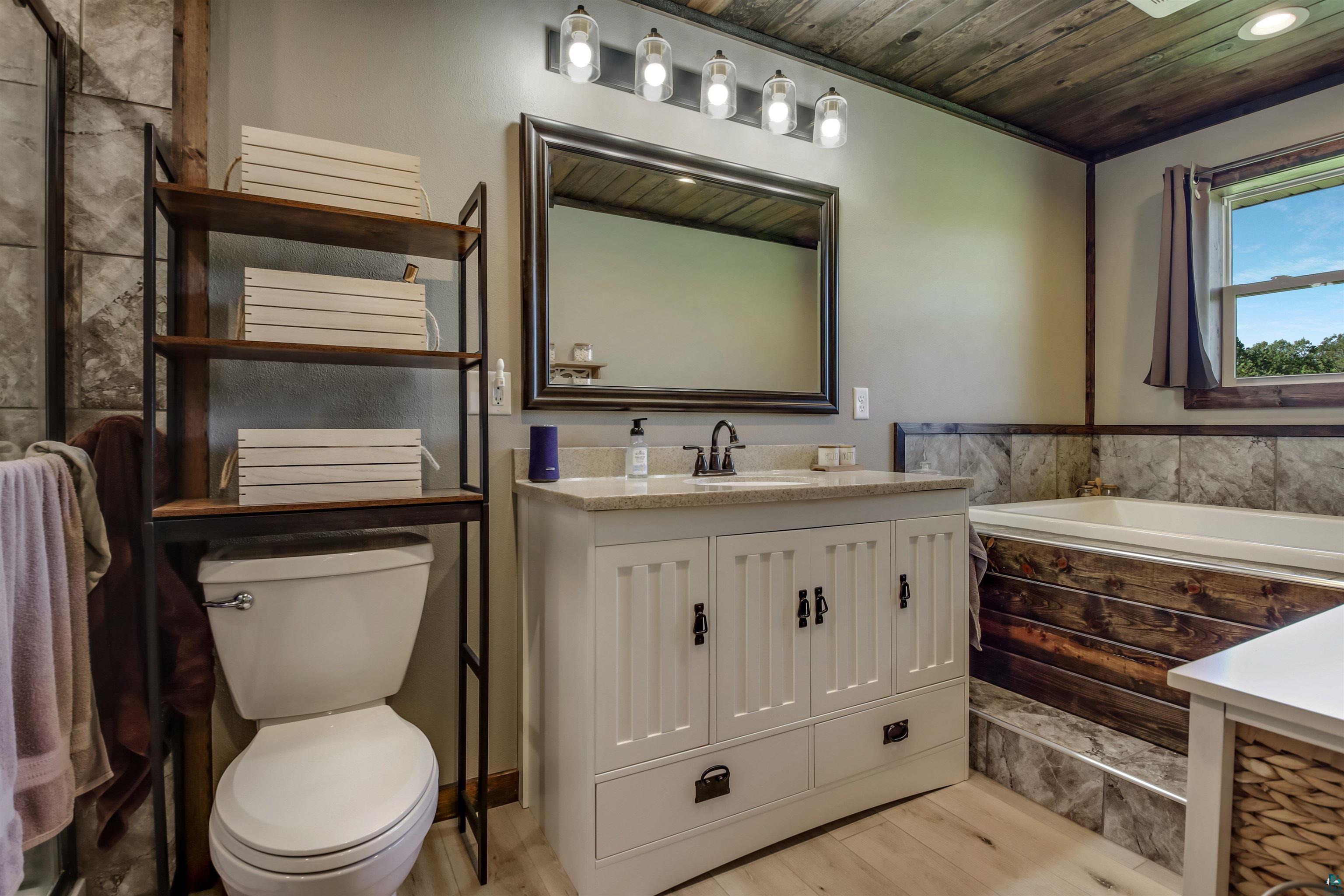 N3685 Fenander Road Spooner, WI 54801 - Photo 27 of 38 Bathroom with toilet, hardwood / wood-style floors, a tub, vanity, and wood ceiling