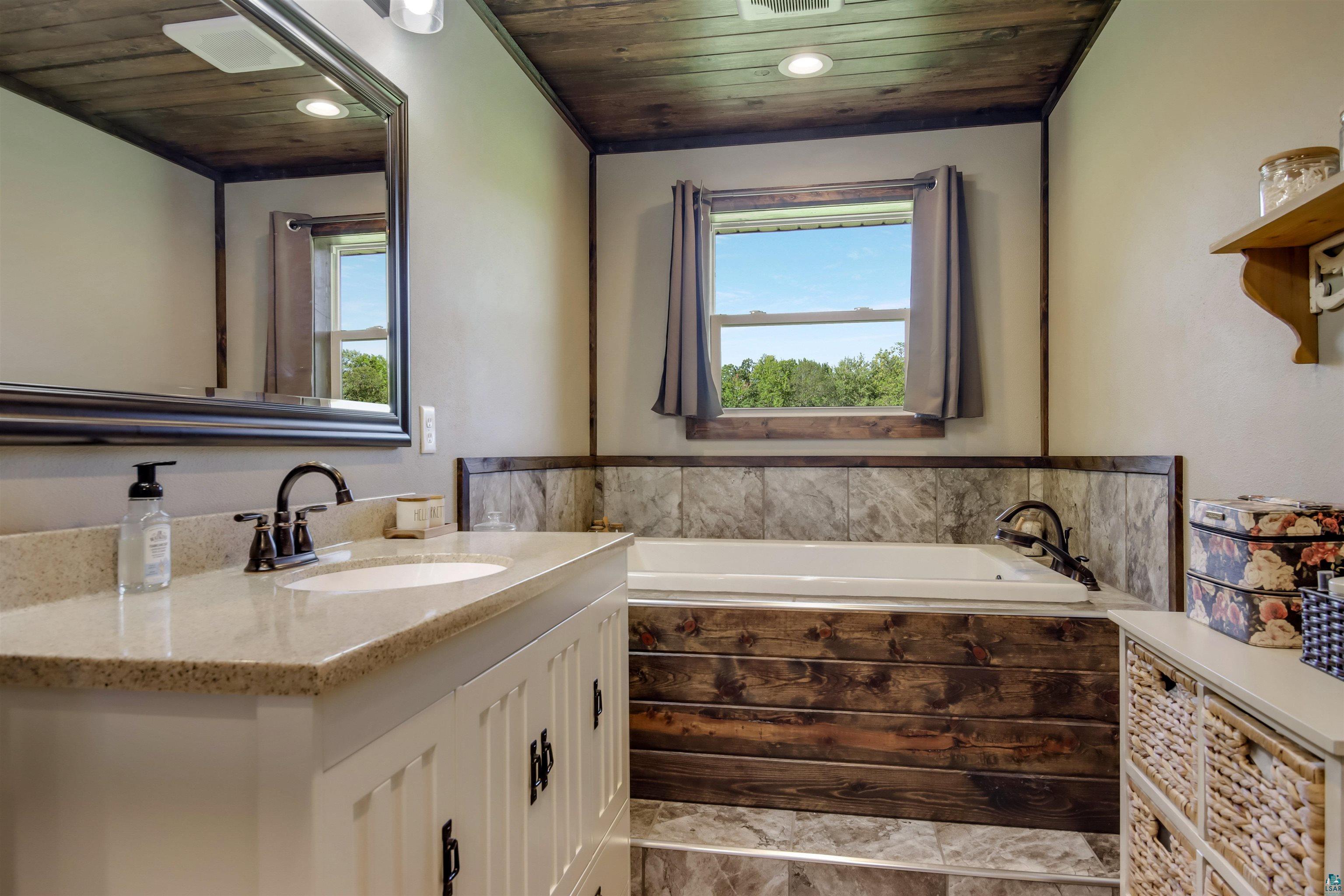 N3685 Fenander Road Spooner, WI 54801 - Photo 28 of 38 Bathroom with wood ceiling, vanity, and tiled tub