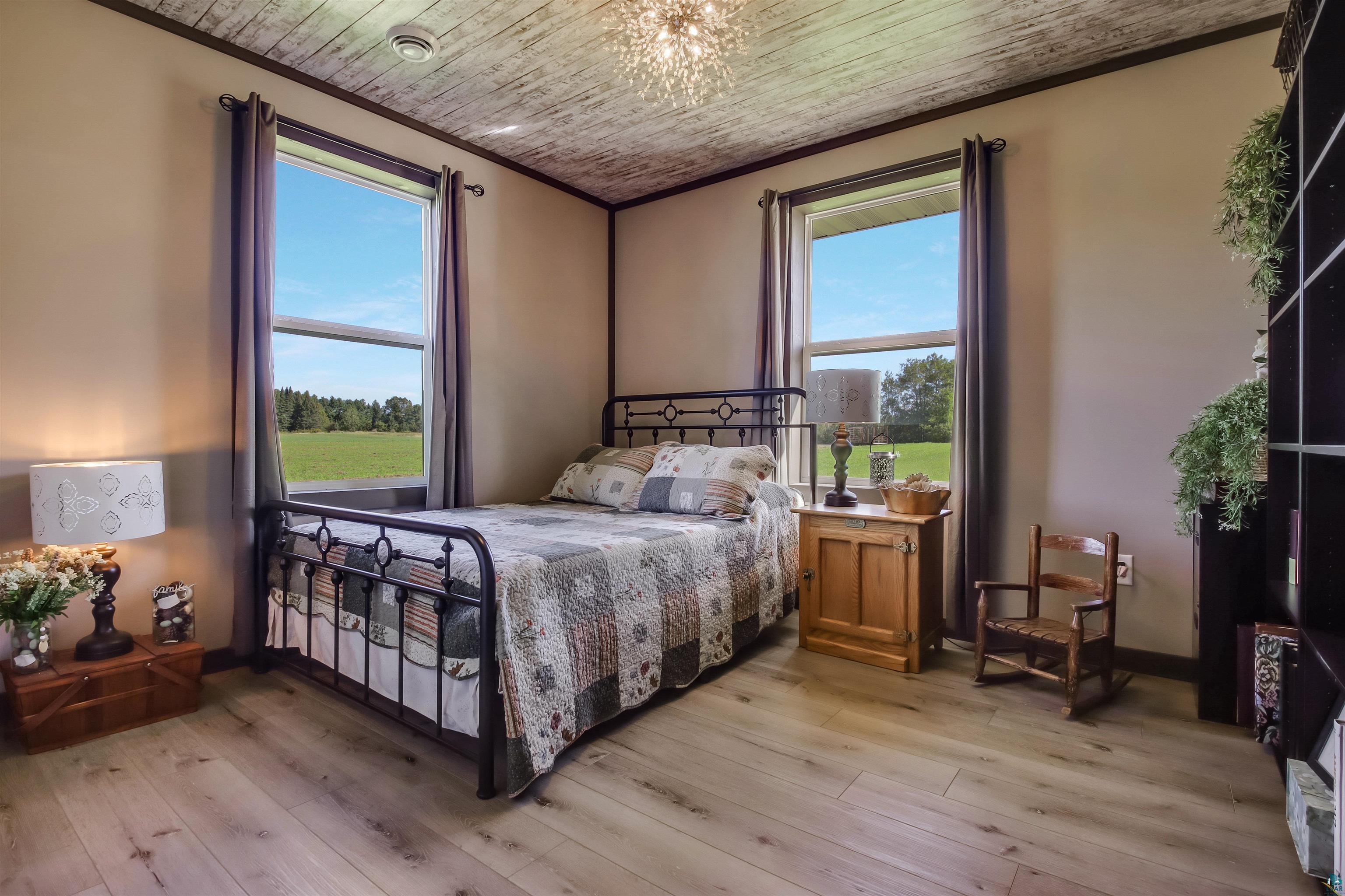 N3685 Fenander Road Spooner, WI 54801 - Photo 30 of 38 Bedroom with light wood-type flooring, multiple windows, a chandelier, and ornamental molding