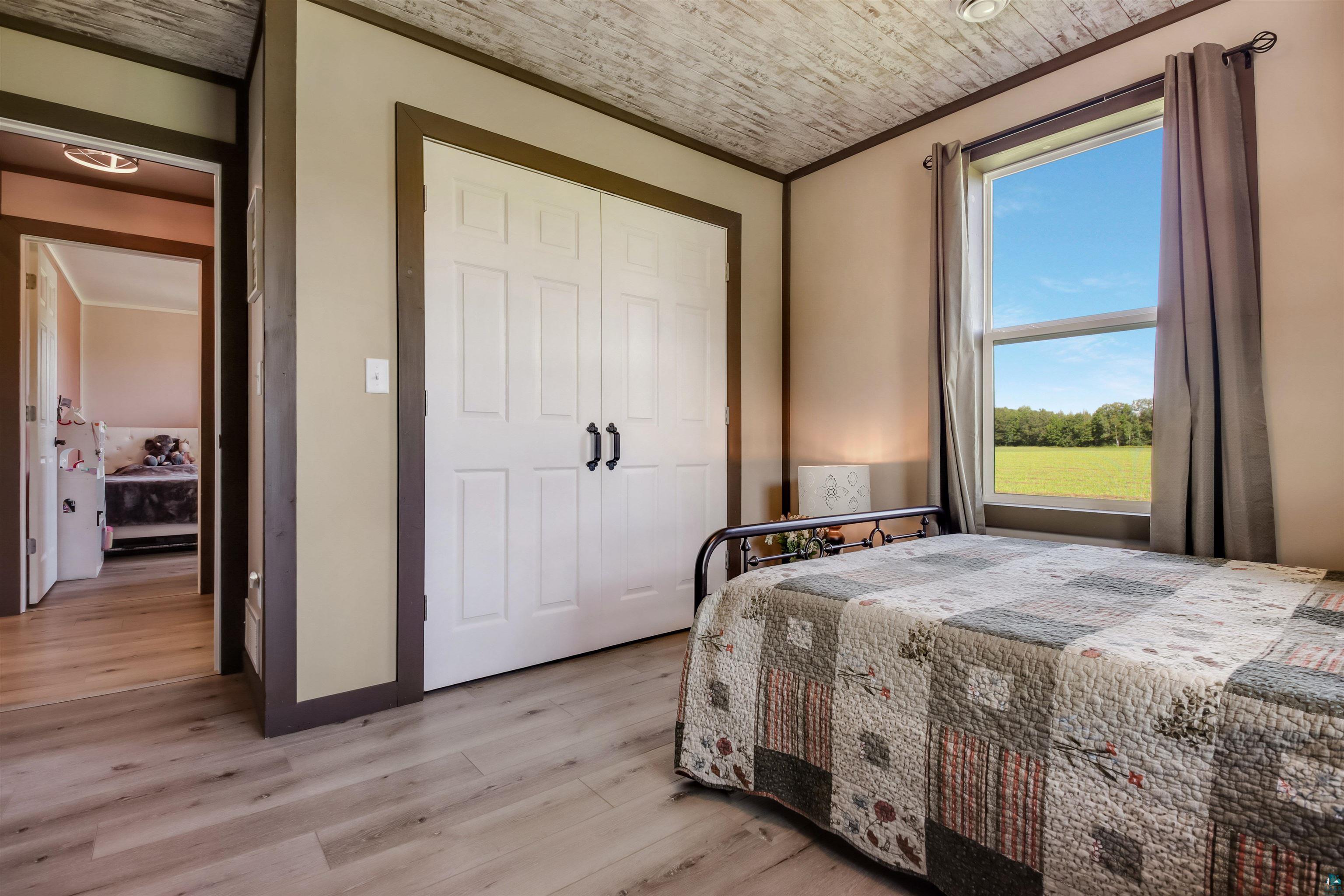 N3685 Fenander Road Spooner, WI 54801 - Photo 31 of 38 Bedroom featuring light wood-type flooring, multiple windows, crown molding, and a closet